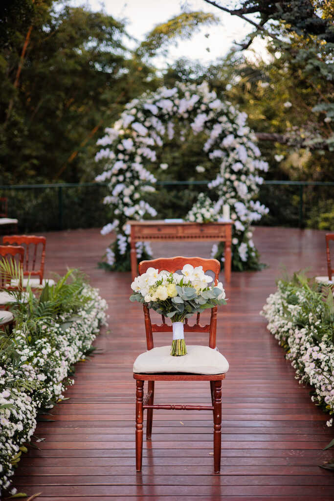 cadeira com buquê branco e ao fundo altar com flores brancas