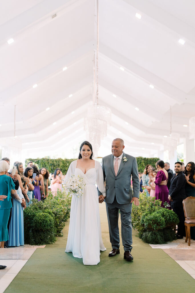 entrada da noiva com vestido com manga longa ao lado do pai com terno cinza com gravata rosê
