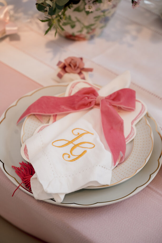 prato com guardanapo bordado com iniciais do casal amarrado com laço cor de rosa