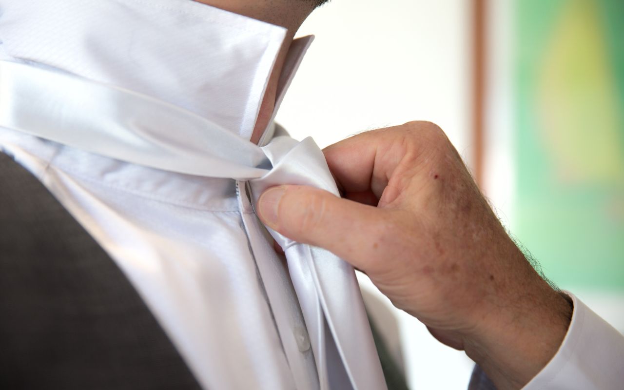 homem ajeitando gravata branca de cetim