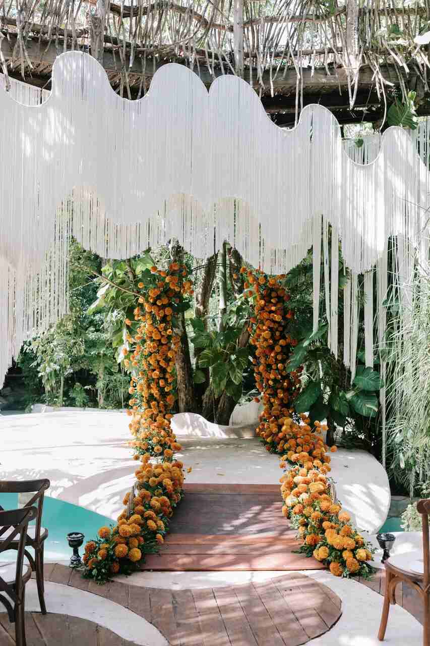 Decoração de casamento com flores laranja preenchendo o corredor
