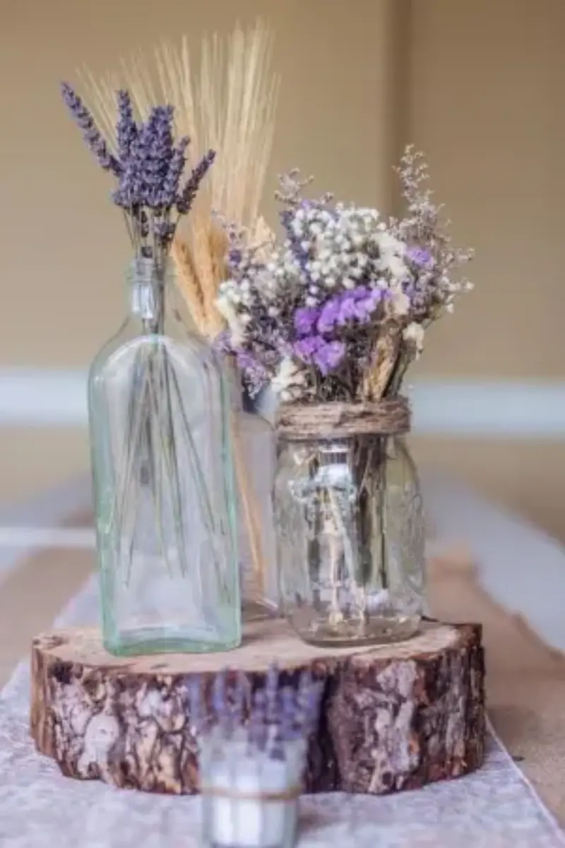dois vidros colocados em cima de um tronco de &aacute;rvore com lavanda para decorar a mesa