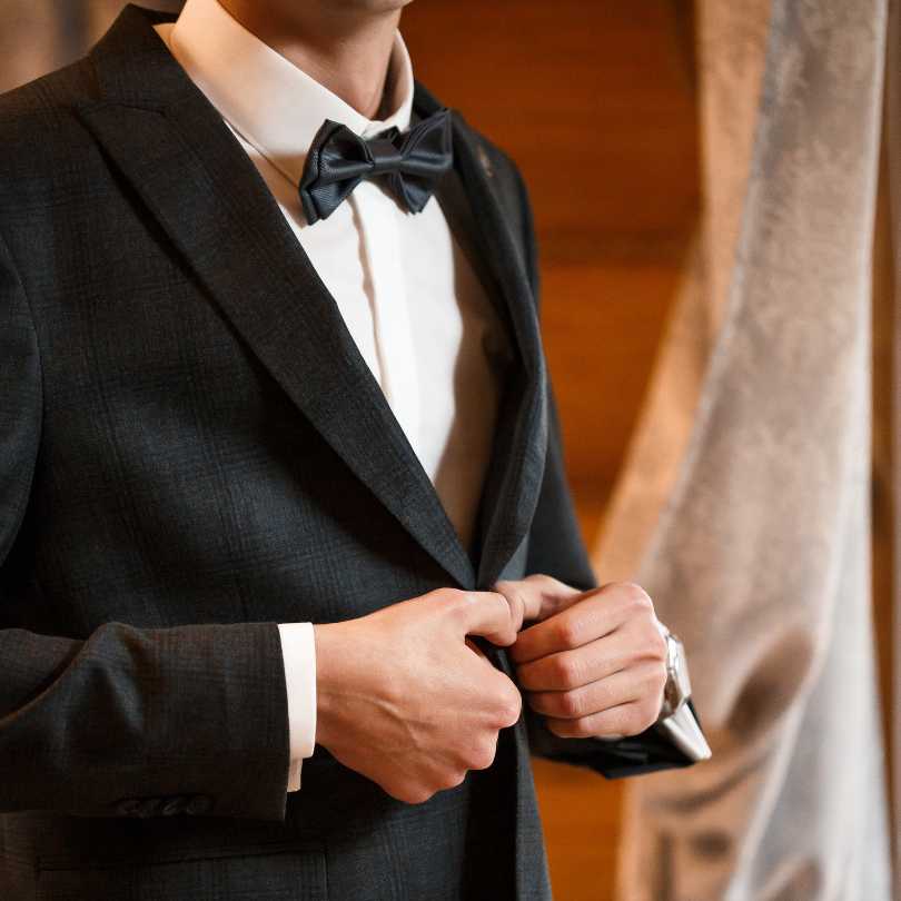  homem com terno preto, camisa branca e gravata borboleta preta
