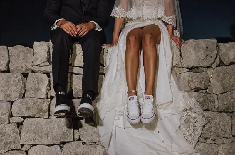  casal vestindo trajes formais de casamento combinados com tênis casuais.