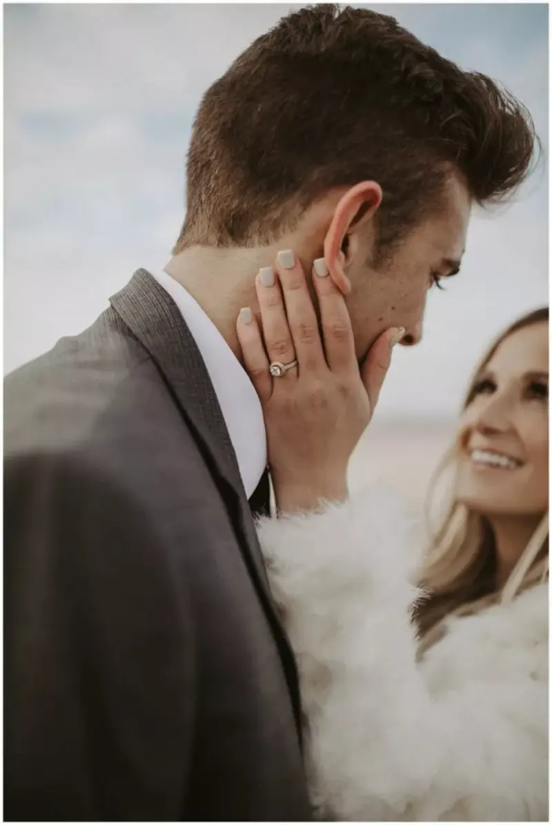 noivo com mão no rosto do noivo mostrando o anel de casamento