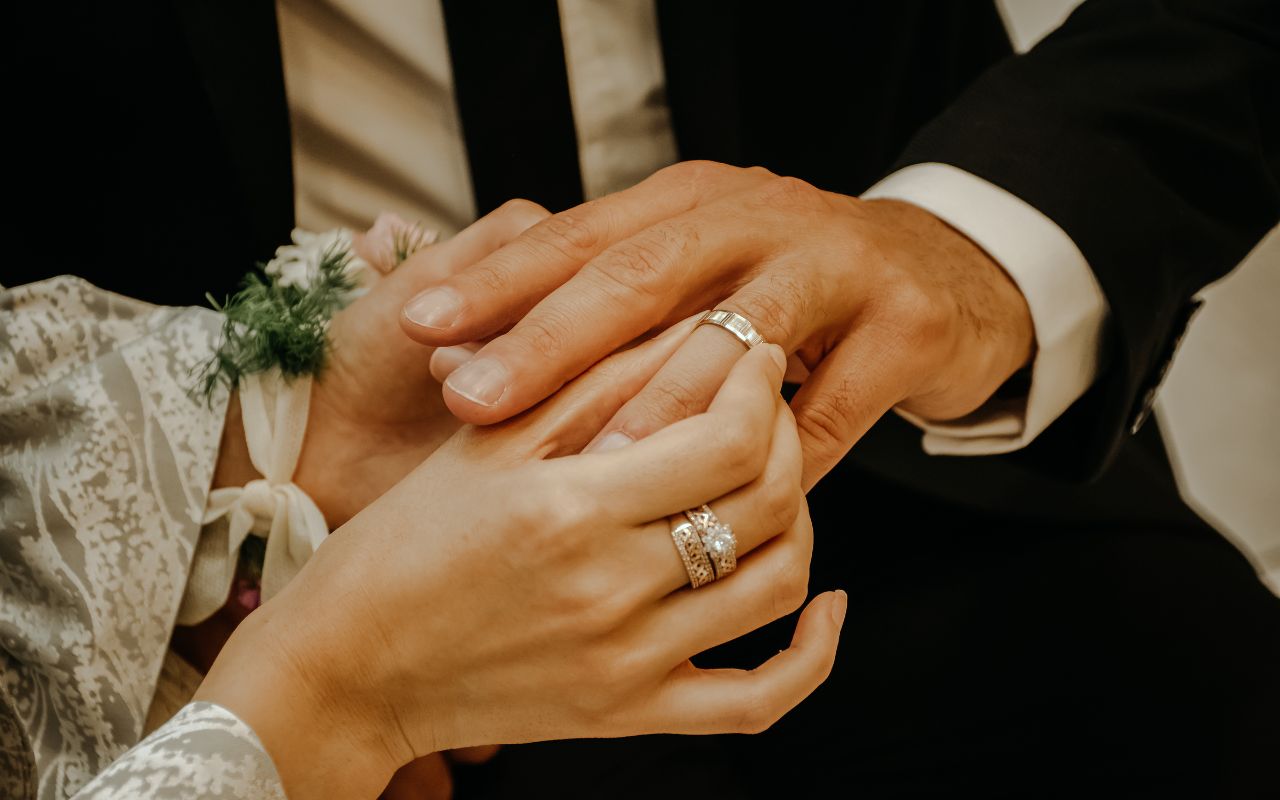 noiva colocando aliança de casamento prata no dedo do noivo