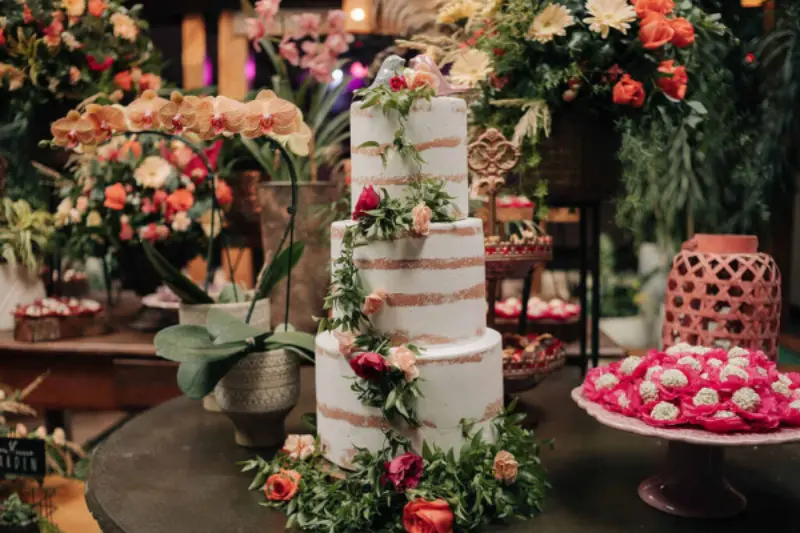 bolo de casamento rústica com um bolo estilo "naked cake" de três andares decorado com flores naturais e folhagens. Com topo do bolo de pássaros