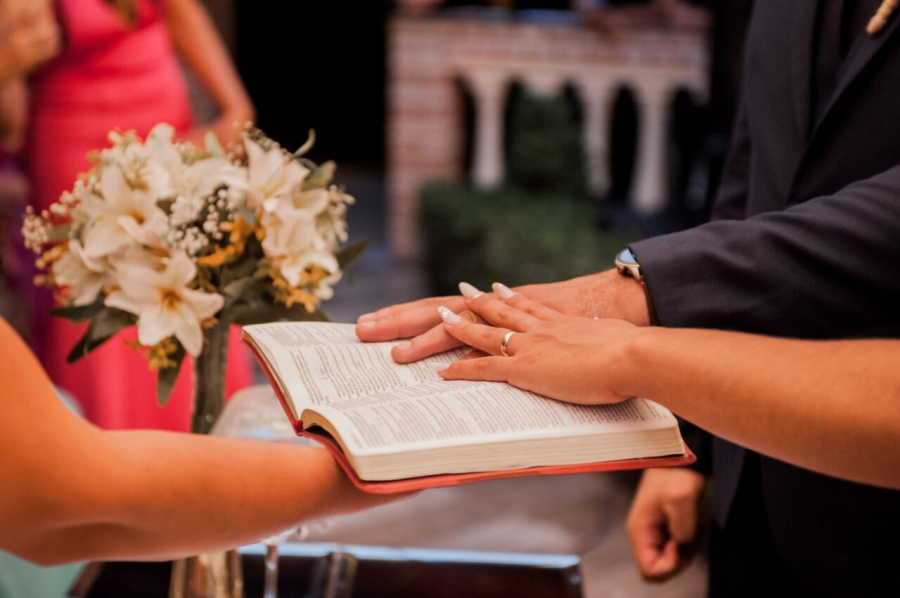 Mãos dos noivos sobre uma Bíblia durante a cerimônia de casamento