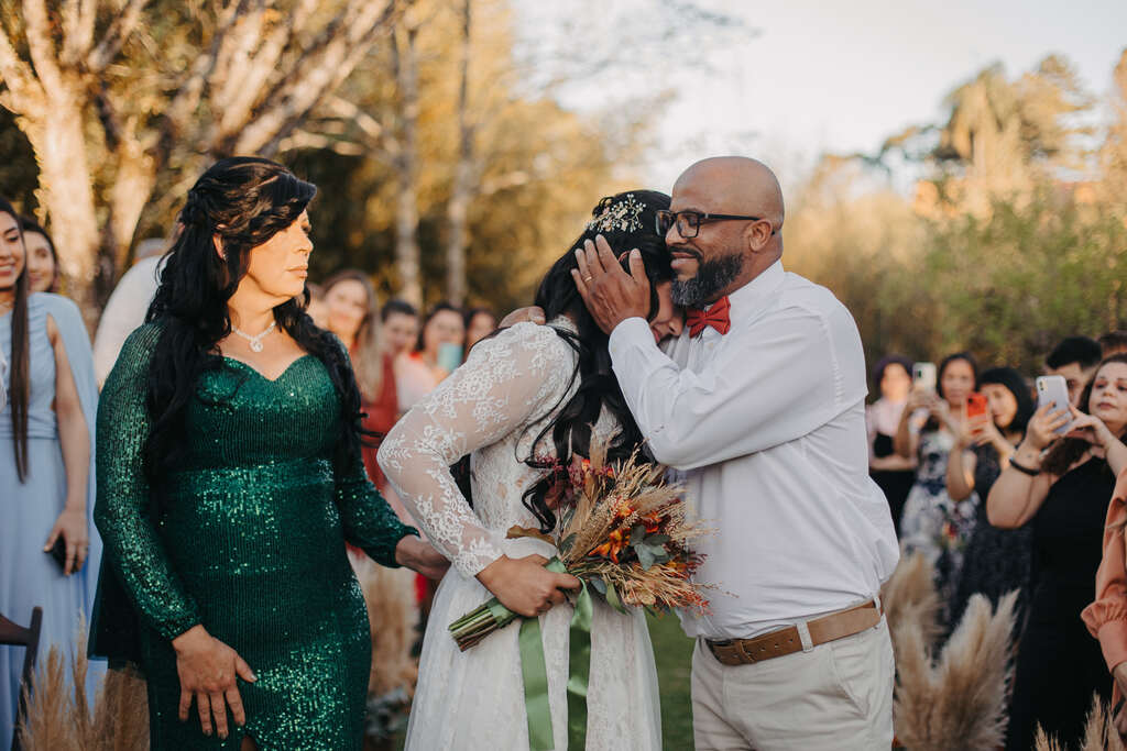 pai da noiva abraçando ela e mãe com vestido verde esmeralda com manga longa e brilhante