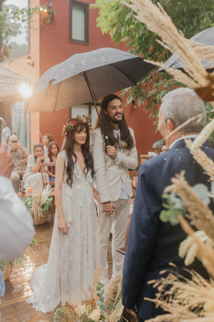 noivos debaixo de guarda chuva na cerimonia de casamento