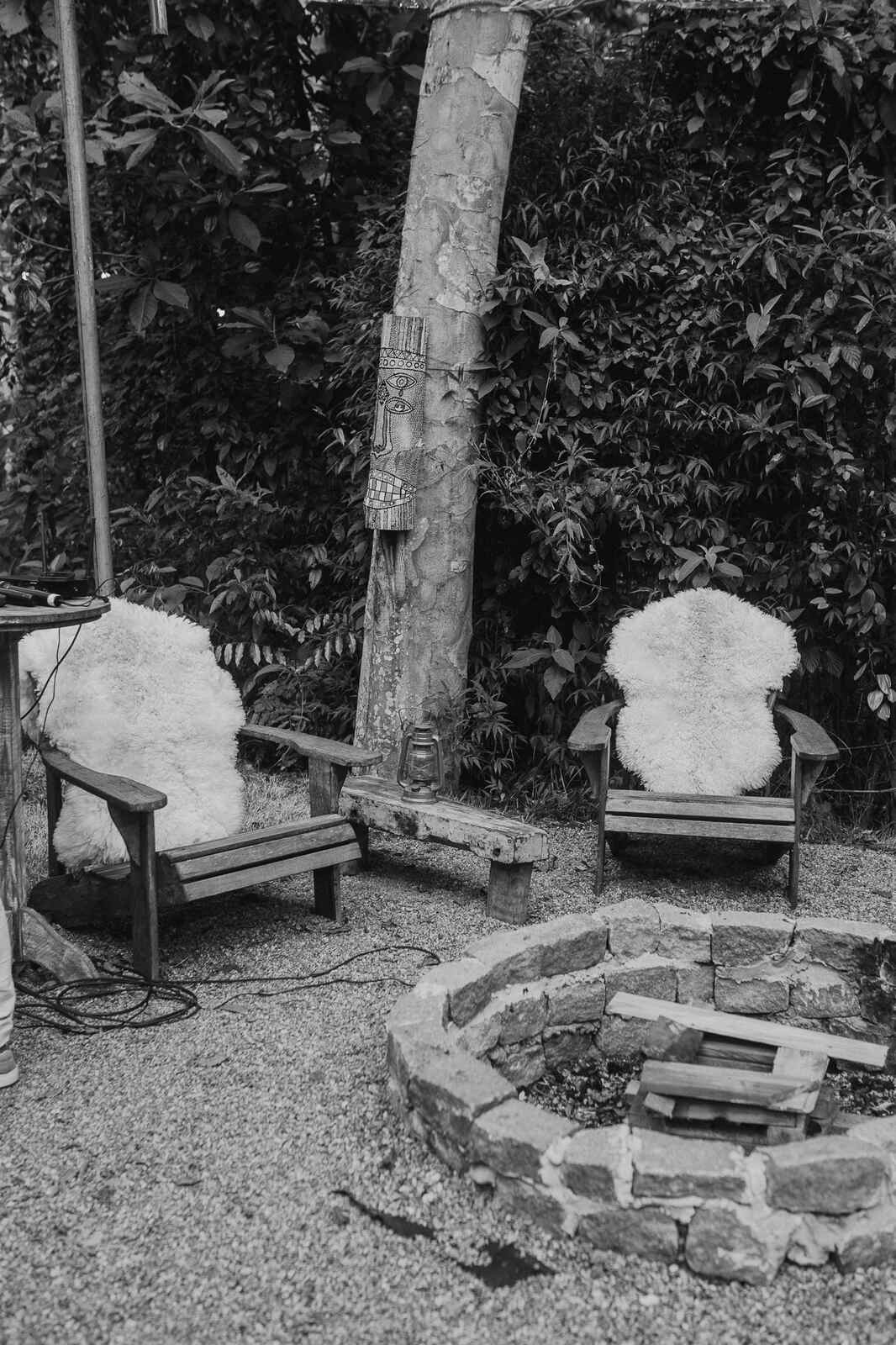 duas cadeiras de madeira com tecido felpudo em volta de espaço para fogueira