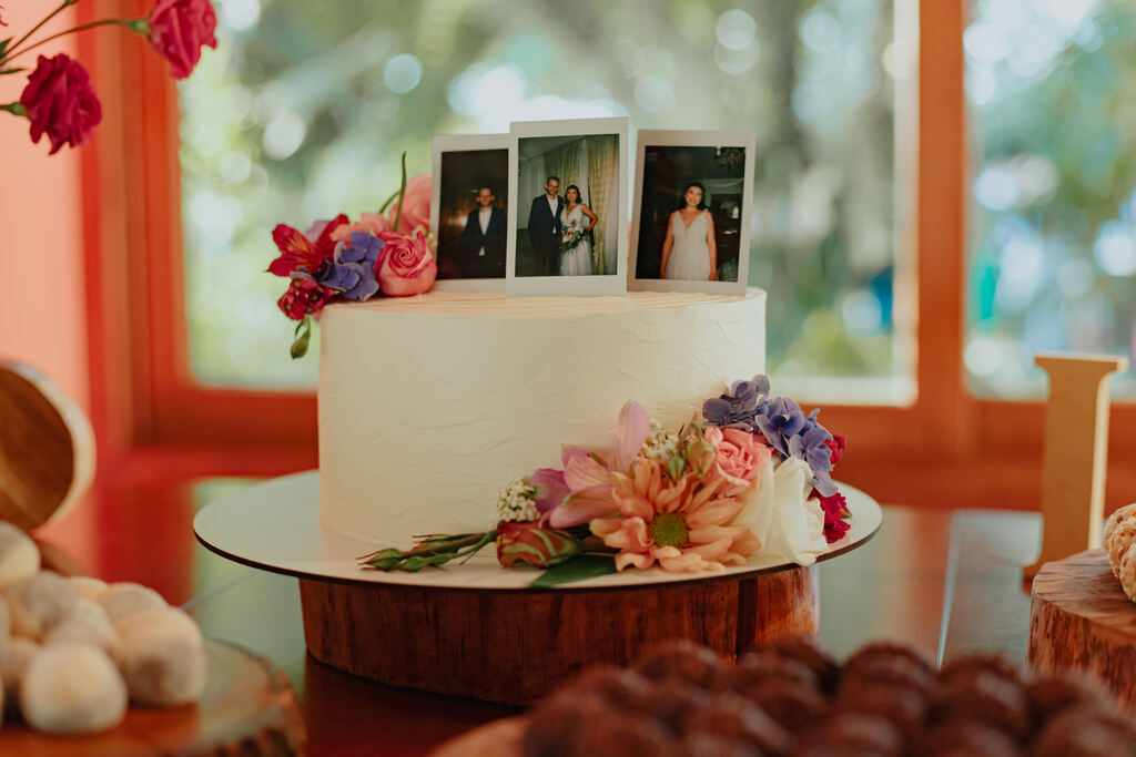 bolo de casamento branco com flores coloridas e topo com fotos polaroide