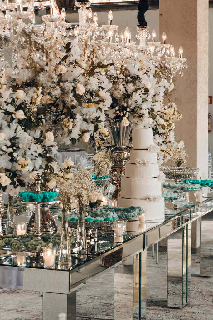 mesa prateada com bolo de casamento e flores brancas