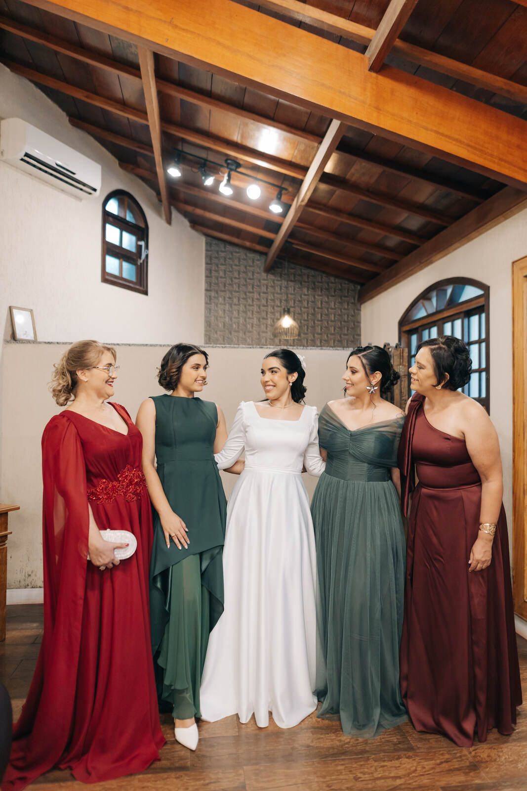 noiva ao lado de duas madrinahs com vestidos verdes e mães com vestidos vermelhos