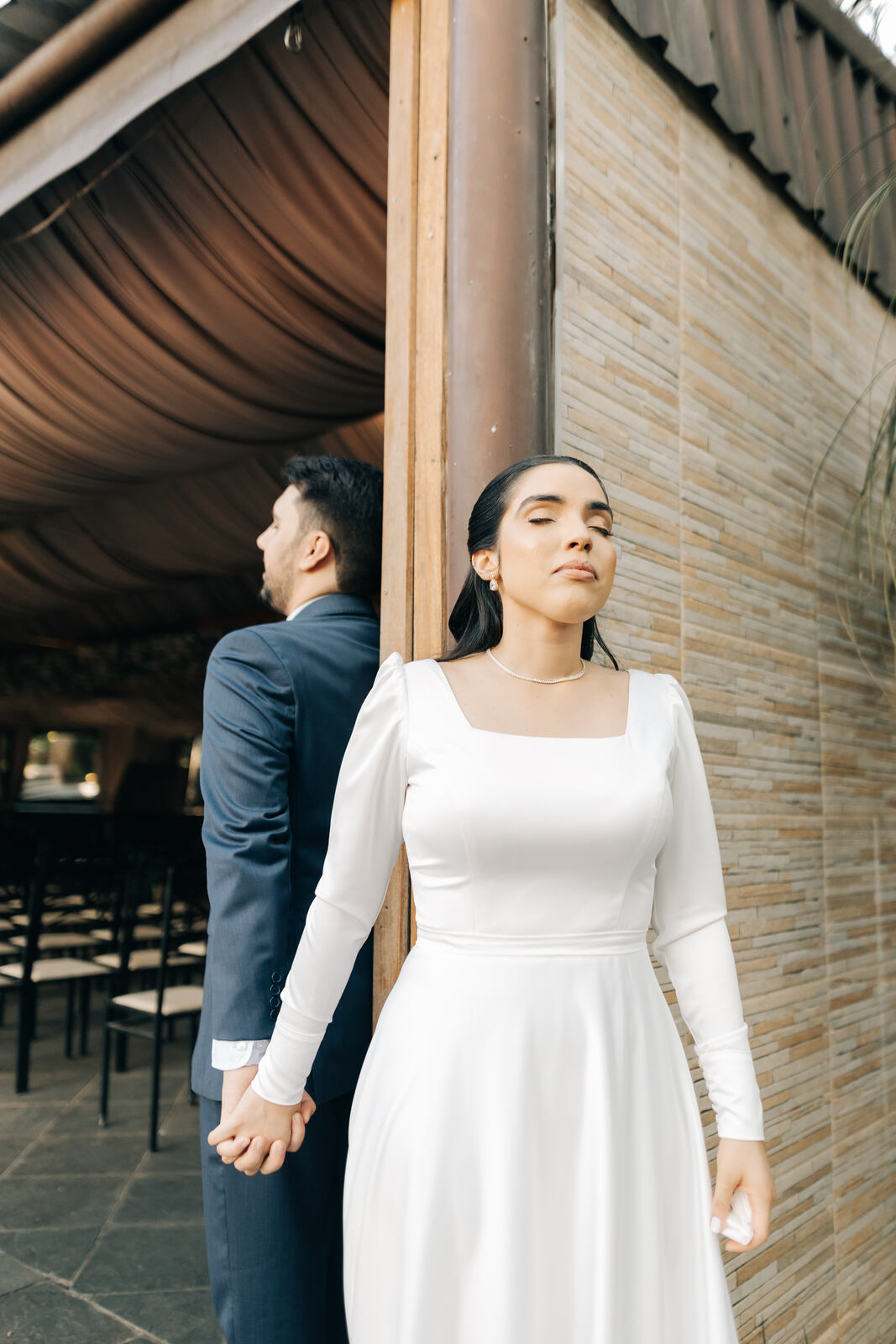 mulher com vestido de noiva minimalista com decote quadrado de mãos dadas com o noivo durante o ensiao first touch