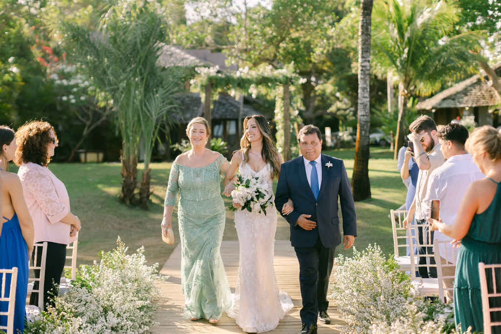 entrada da noiva ao lado da mãe com vestido verde claro e pai com terno preto e gravata azul