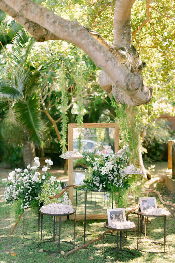 cantinho do bem-casado com várias mesinhas e mesas suspensas e espelho grande ao fundo debaixo de árvore