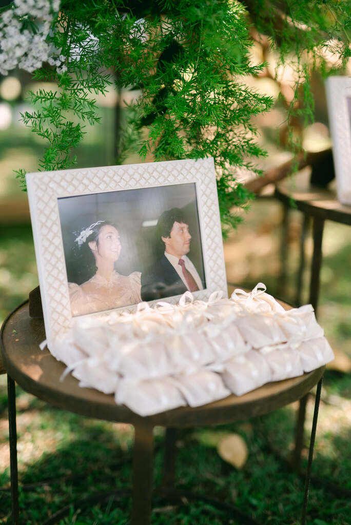 mesa redonda pequena com retrato de foto dos pais dos noivos e bem-casados na embalagem branca
