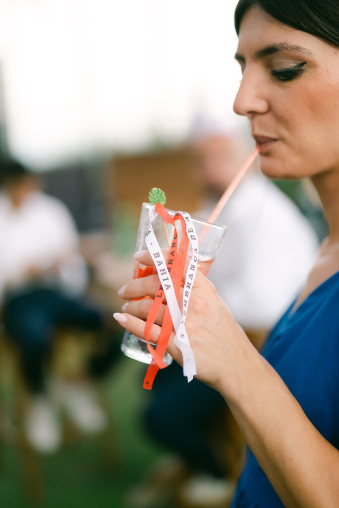 mulher tomando bebida com fitinhas brancas e vermelhas típicas da bahia