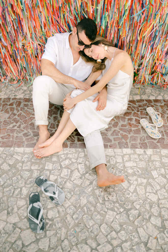 casal sentado perto de muro com fitinhas coloridas