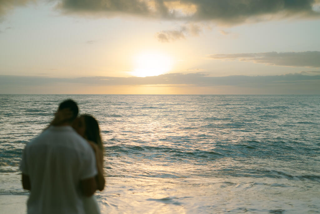 noivos abraçados na praia ao nascer do sol