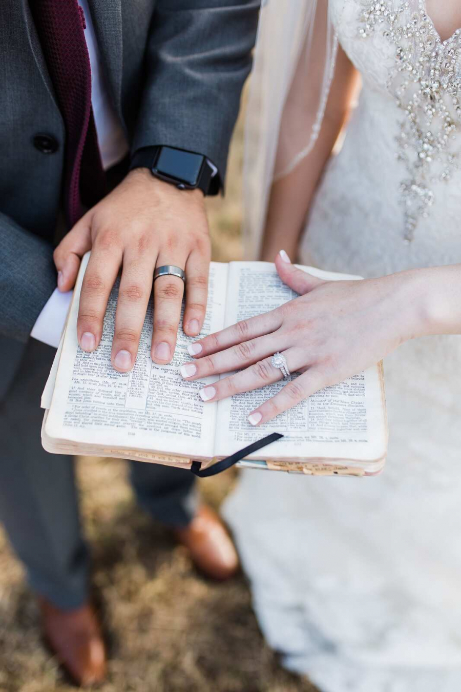 Mãos do noivo e da noiva sobre uma Bíblia aberta