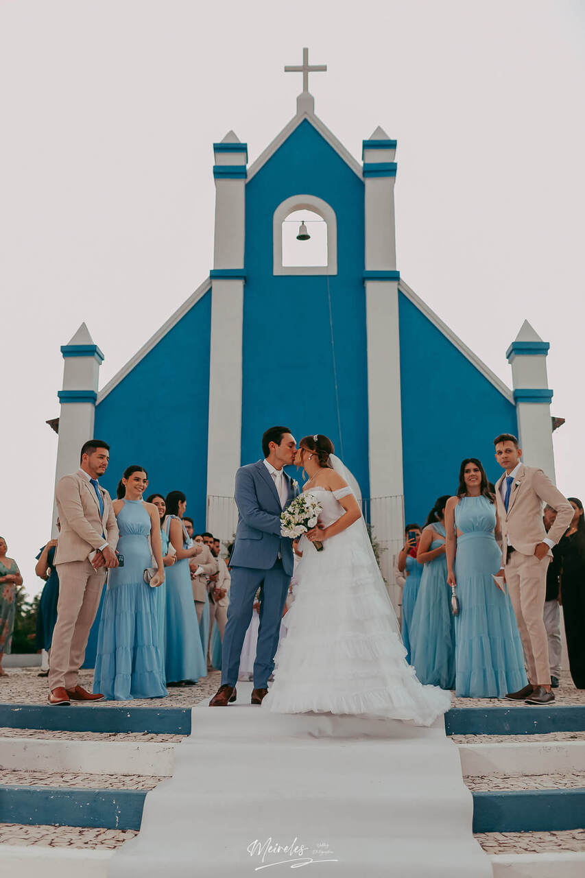 noivos se beijando durante saída de cerimônia religiosa em casamento clássico na igreja