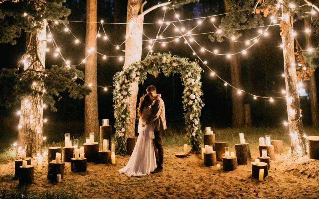 casal em casamento a noite ao ar livre com no altar com velas e varal de luzes