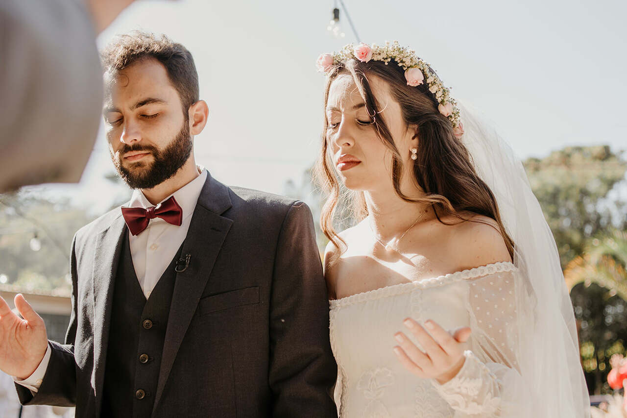 Casal de noivos orando com as mãos levantadas