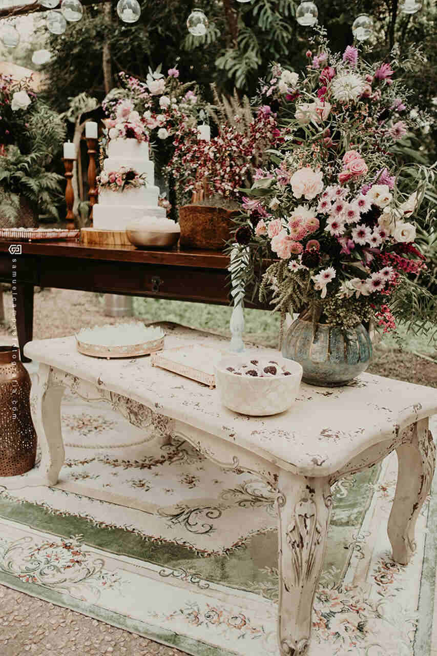 Mesa do bolo com uma mesa vintage menor branca à sua frente