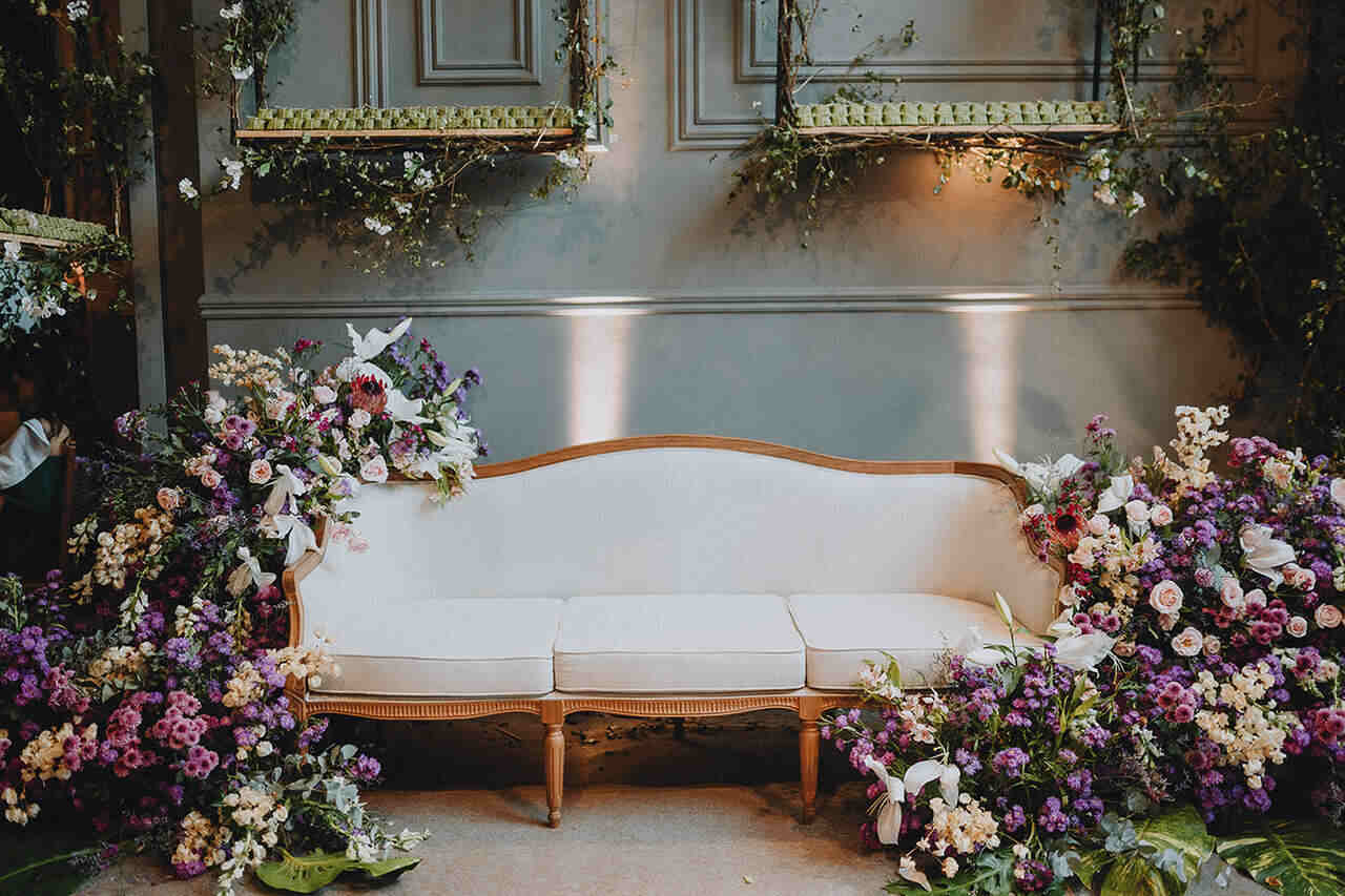 Cenário com um sofá de estofado claro com flores em volta