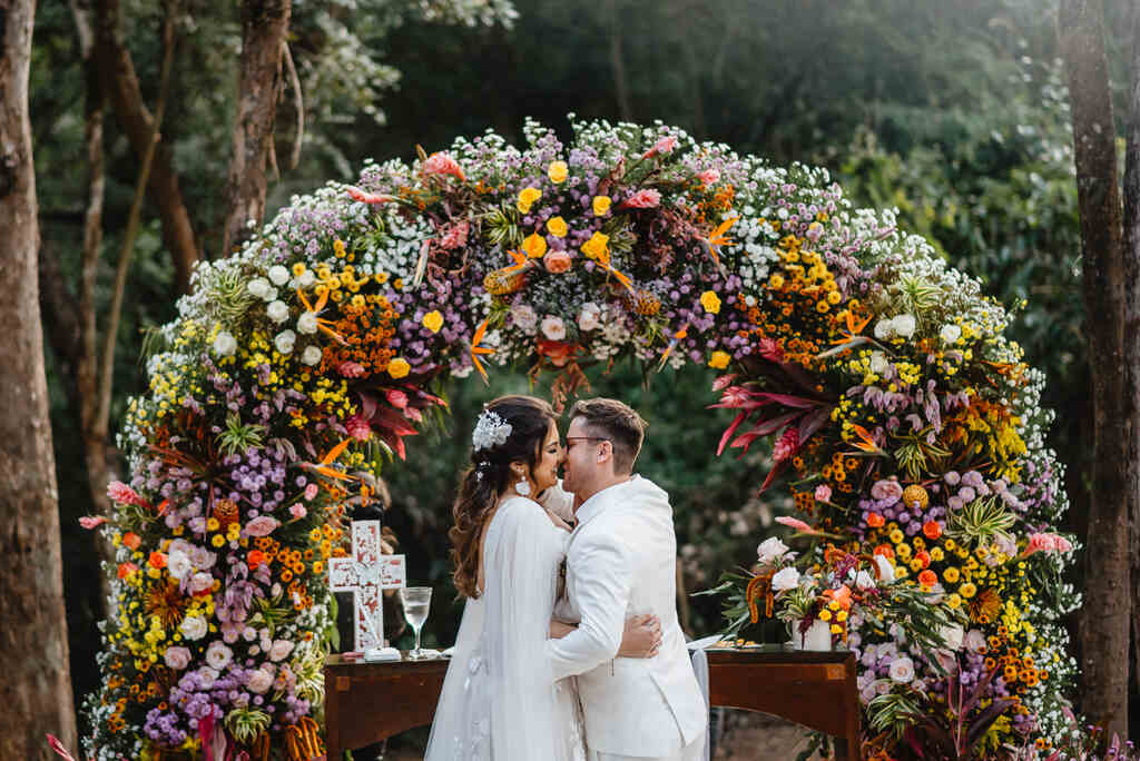 noivos se beijando no altar com flores coloridas
