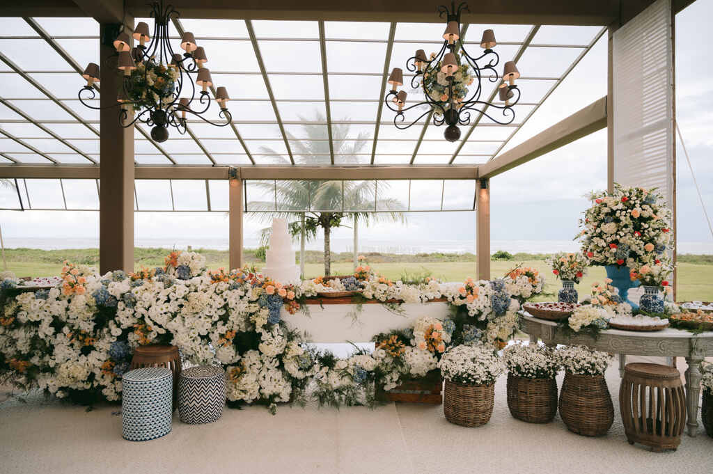salão coberto com mesa do bolo com flores brancas laranjas e azuis