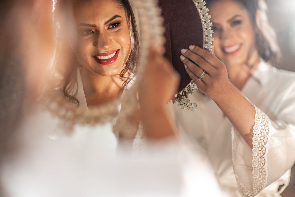 noiva com robe branco se olhando no espelho
