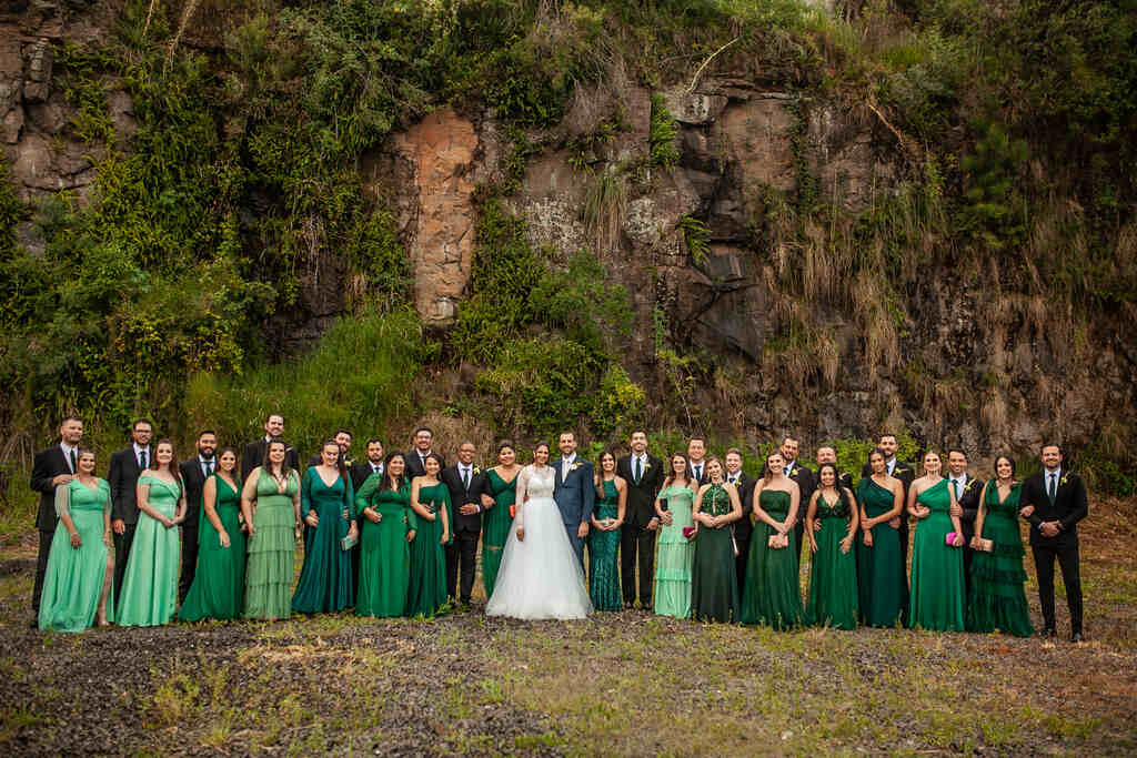 noivos ao lado dos padrinhos de terno preto e madrinhas com vestidos verdes