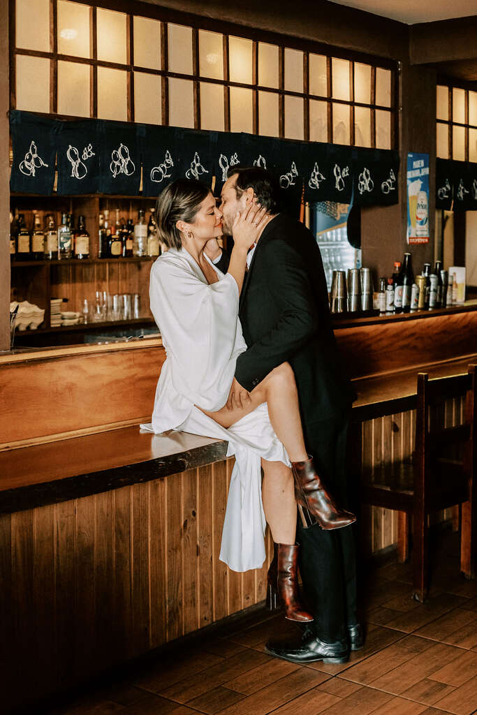 noivos se beijando no balcão do bar