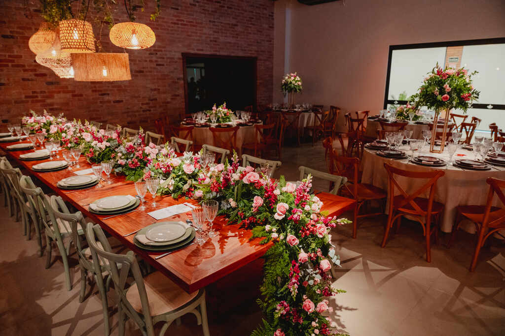 salão com mesa decorada com flores cor de rosa