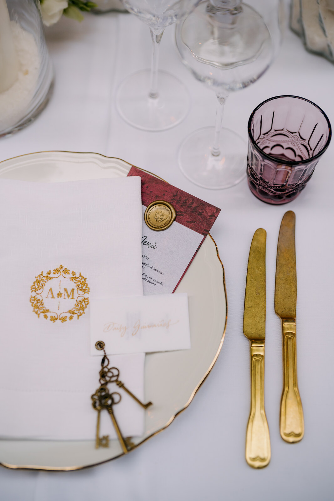 mesa posta com facas douradas copo roxo e guardanapo com bordado dourado