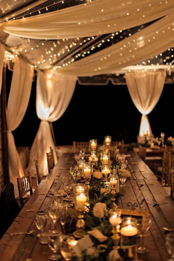mesa de jantar decorada com velas lâmpadas e tecidos