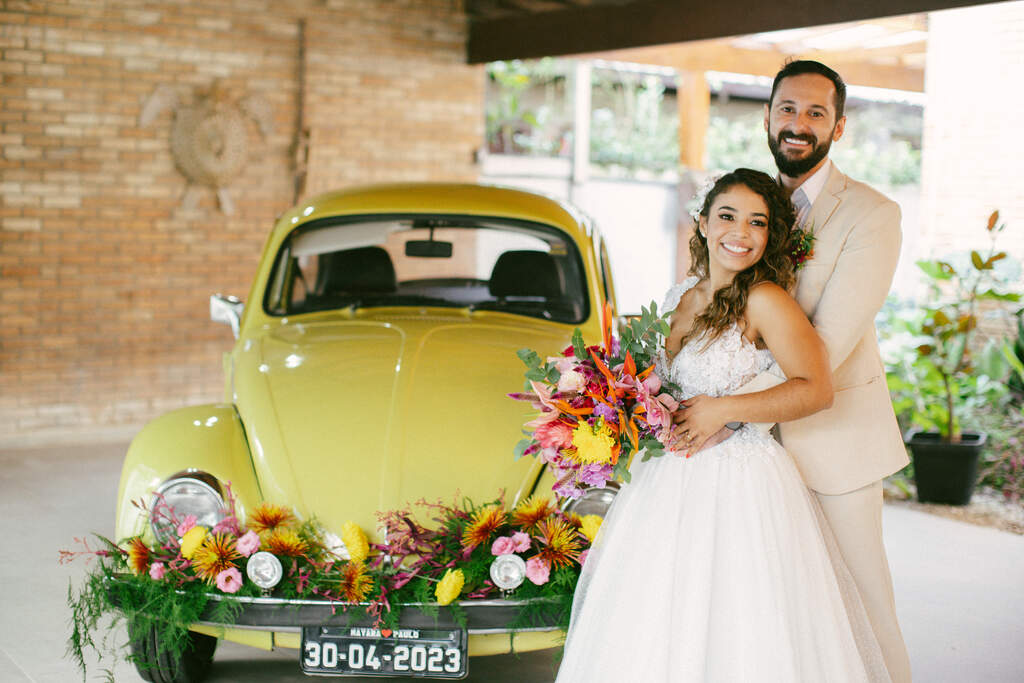 noivos abraçados posando para a foto e ao fundo um fusca amarelo