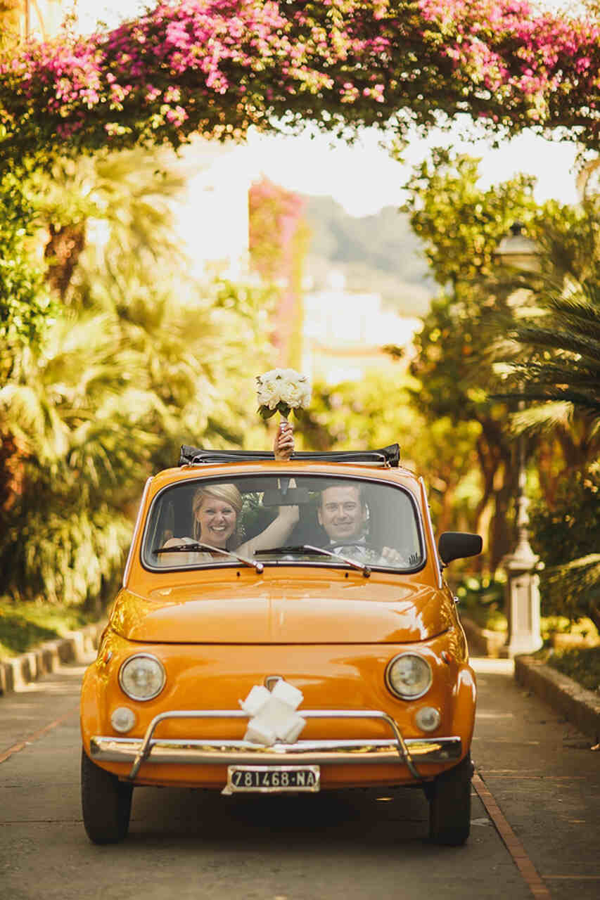 Carro vintage amarelo com o casal de noivos 