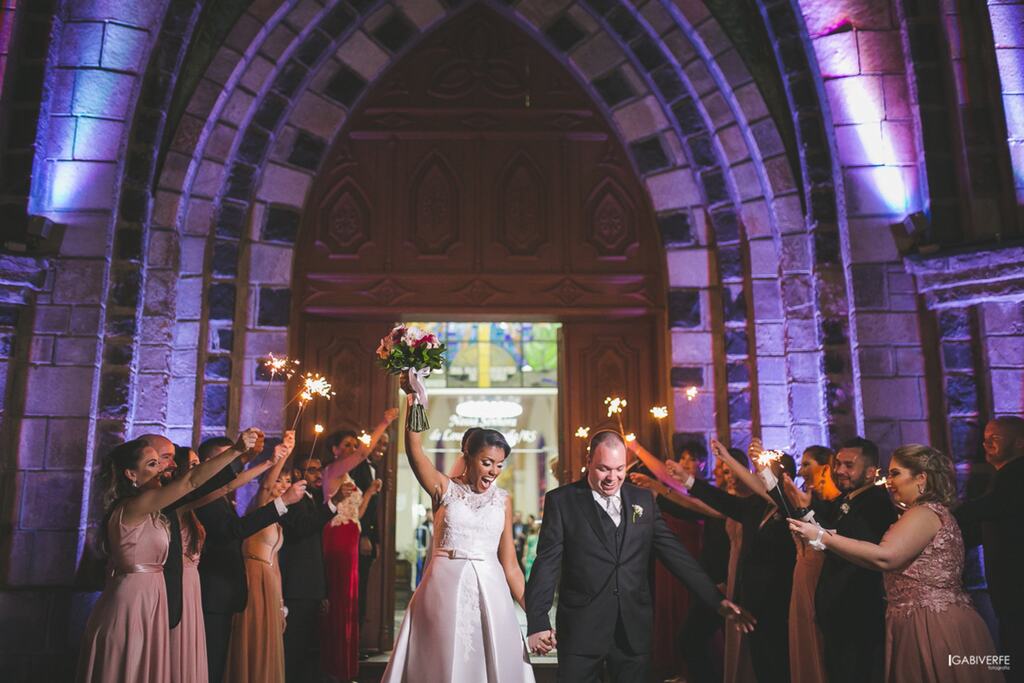 Casal de noivos saindo da catedral com os padrinhos ao redor