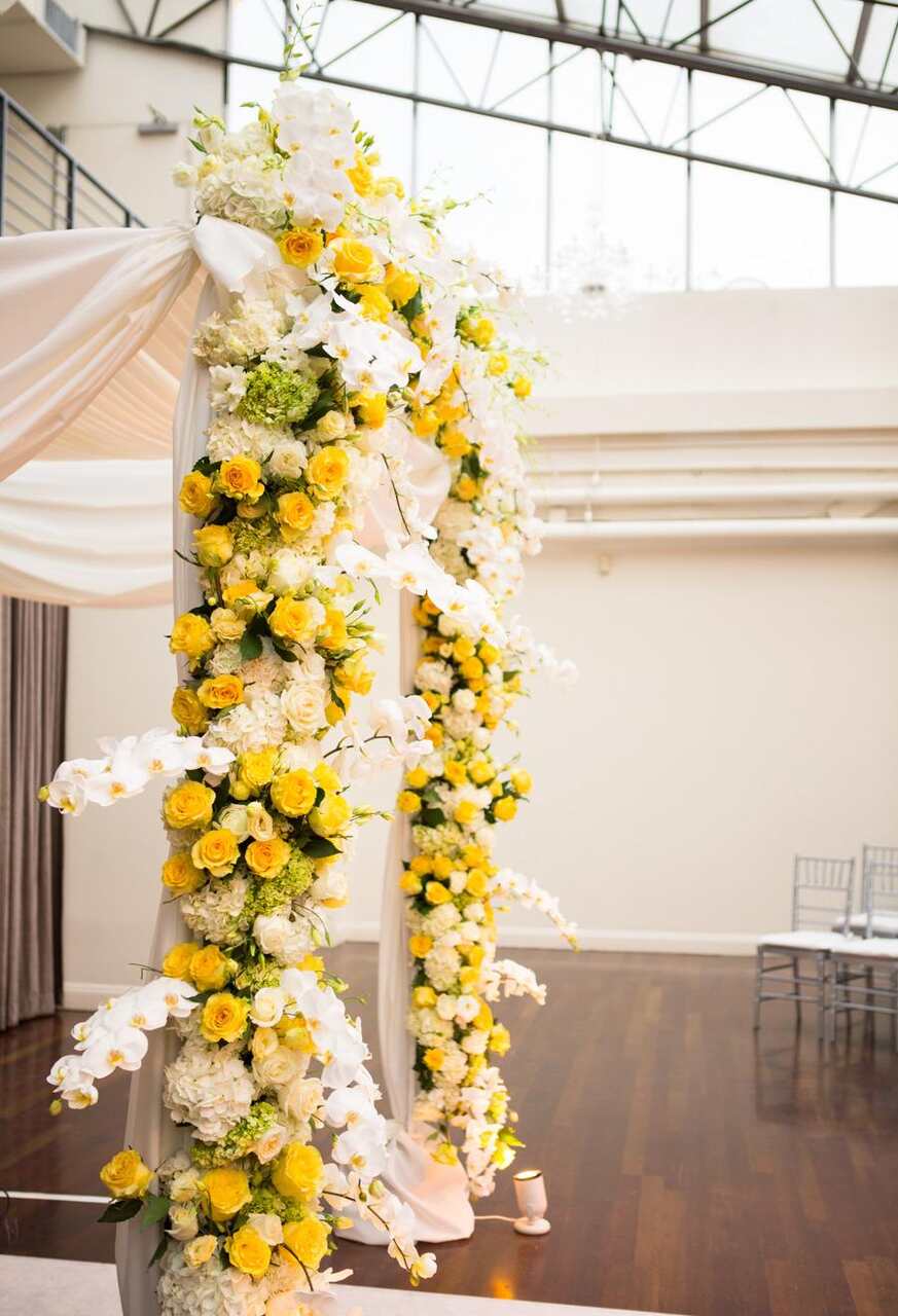 Arcos de flores brancas e amarelas no altar