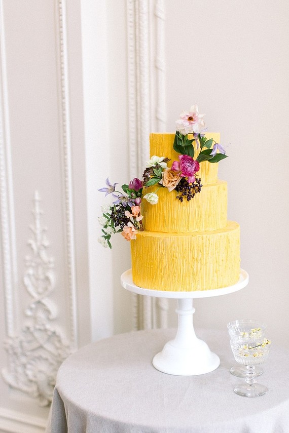 Bolo de 3 andares amarelo com arranjo floral de enfeite