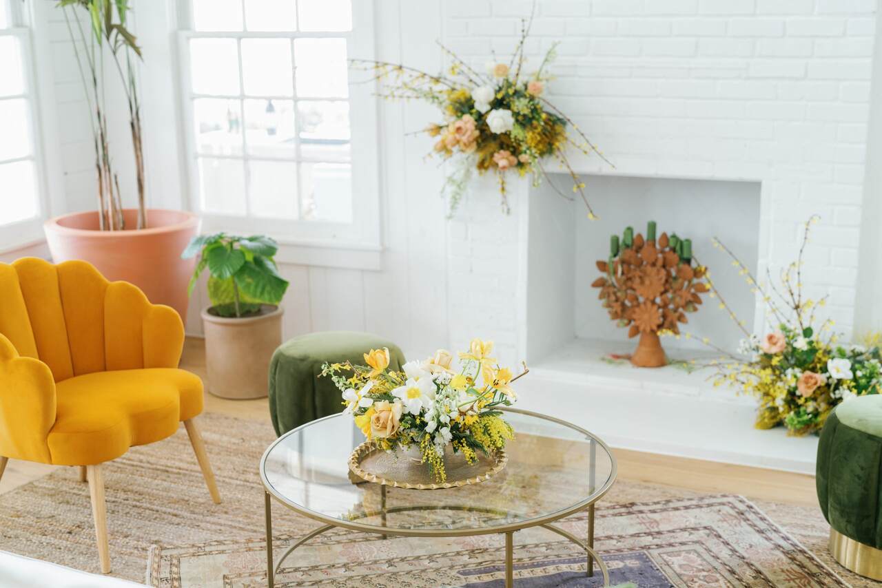 Decoração com estofado amarelo, mesa de centro e arranjos florais com amarelo e branco