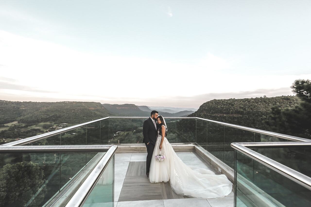 Noivos abraçados em uma plataforma panorâmica do Castelo Saint Andrews, em Gramado