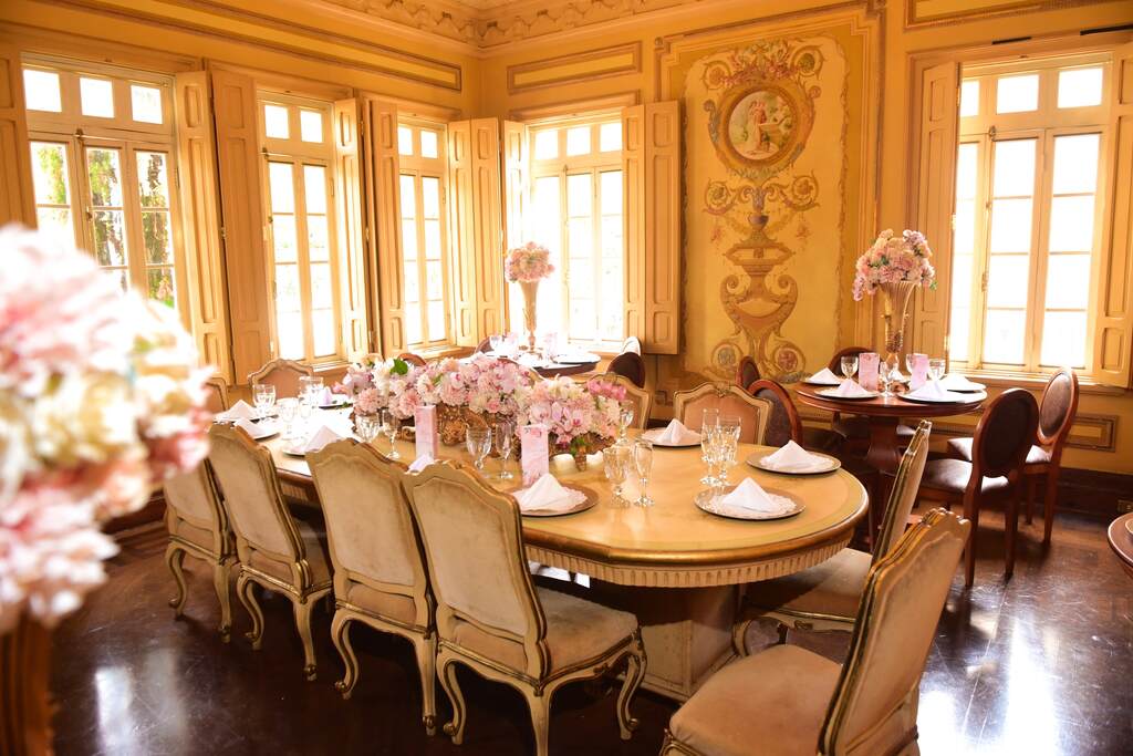 salão antigo com mesa clássica decorad com flores cor de rosa