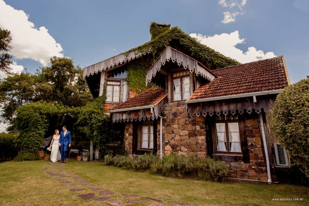 Casal de mãos dadas, andando lado a lado numa casa rústica localizada na Estalagem La Hacienda