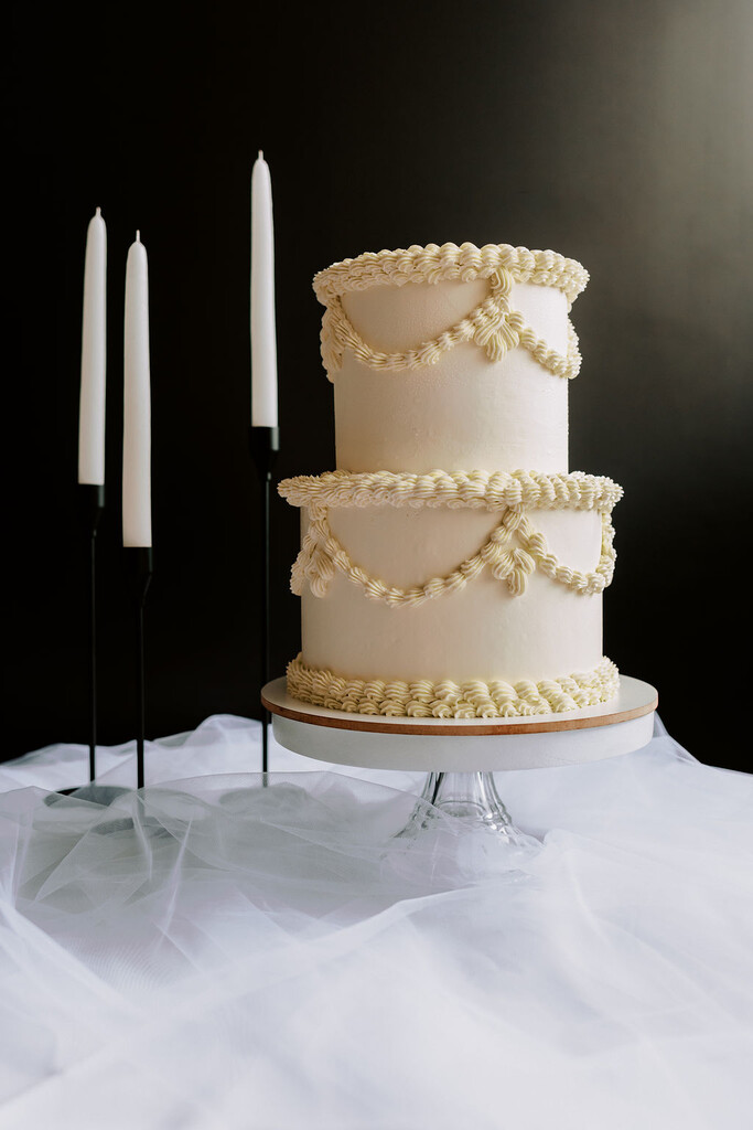 bolo branco vintage ao lado de três velas