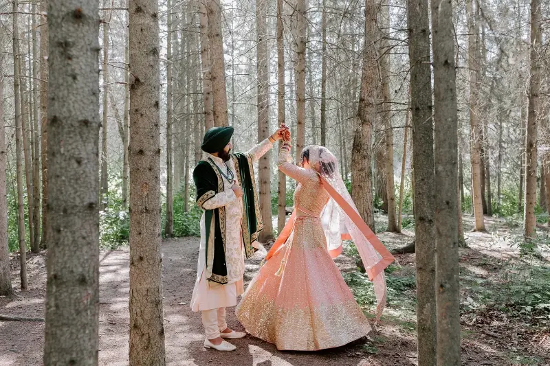 casamento indiano com noivos dançando entre às árvores